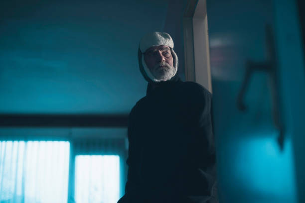istock Man in woolen cap intruding dark living room. 885382610