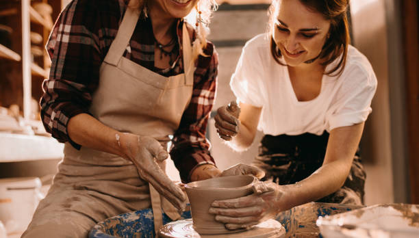 istock Two women at a pottery workshop making clay pots 885390982