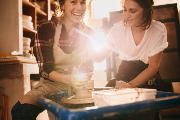 istock Two women at a pottery workshop making clay pots 885391024