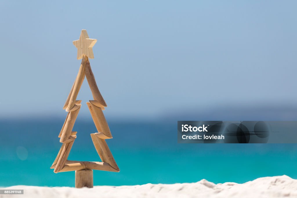 Timber Christmas tree on sandy beach Timber Christmas tree with star sits in pristine white sand with idyllic beach background.  A summer Christmas. Christmas Stock Photo