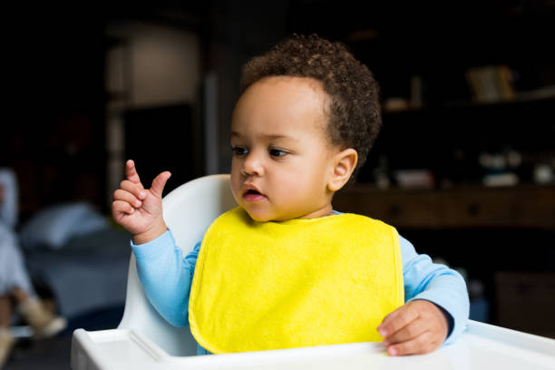 little african american boy in bib little african american boy with yellow bib sitting in baby chair high chair stock pictures, royalty-free photos & images