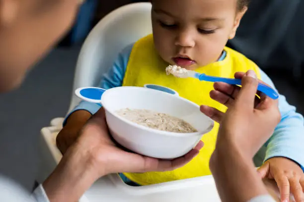 Photo of little son eating porridge