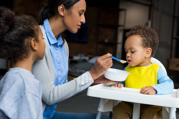 istock mother and daughter feeding baby 885400318