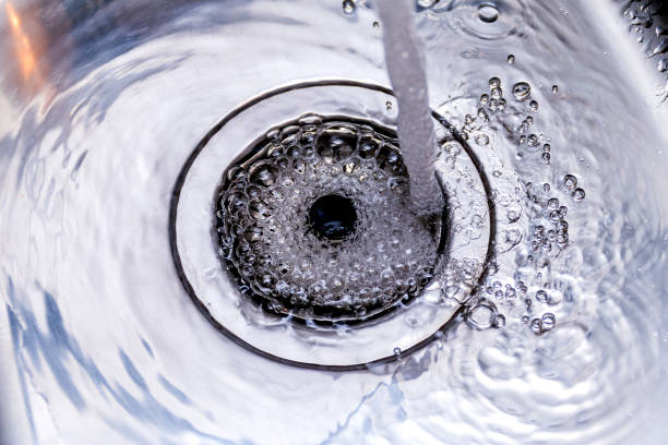 Kitchen sink with running water A stream of clean water flows into the stainless steel sink. Sink plug hole close up macro kitchen sink stock pictures, royalty-free photos & images