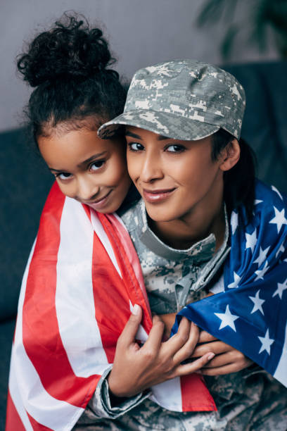 istock daughter and soldier wrapped with american flag 885418502