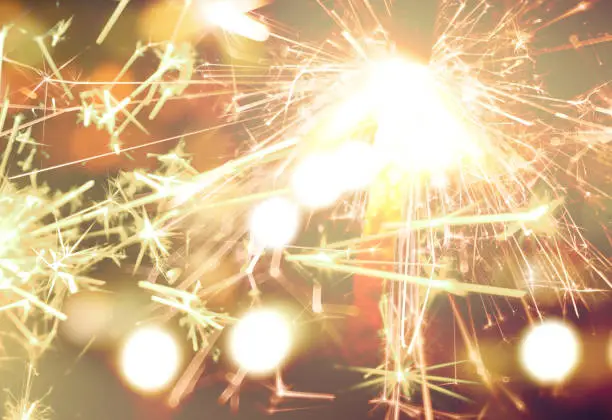 Photo of sparkler on gold bokeh background macro close up