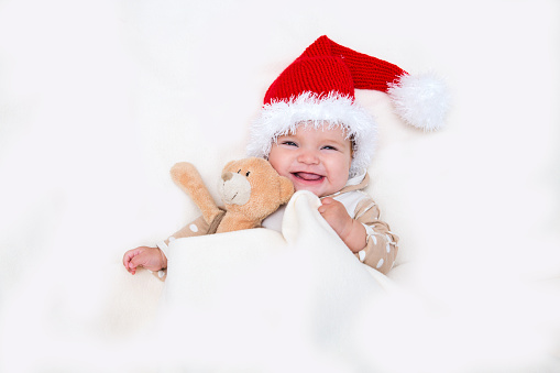 The cheerful Christmas baby to a Santa hat and Teddie's bear