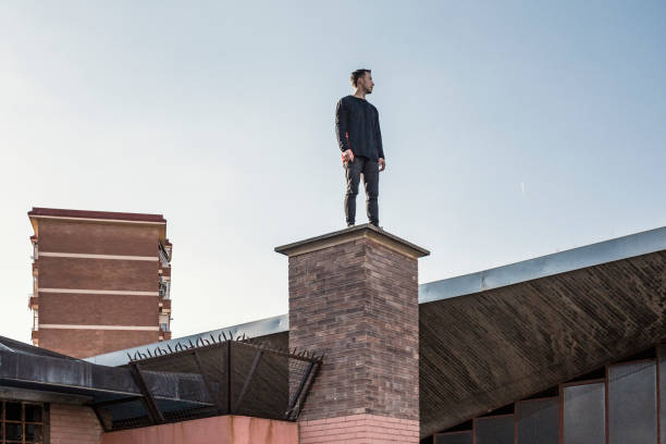 человек, практикующий паркур в городе - men on roof стоковые фото и изображения