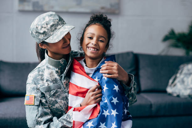 istock soldier and daughter wrapped with american flag 885429926