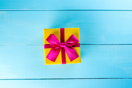 Present box on blue background greeting card holidays concept.