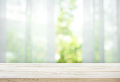 Mesa de madera en desenfoque de cortina con jardín vista de ventana photo
