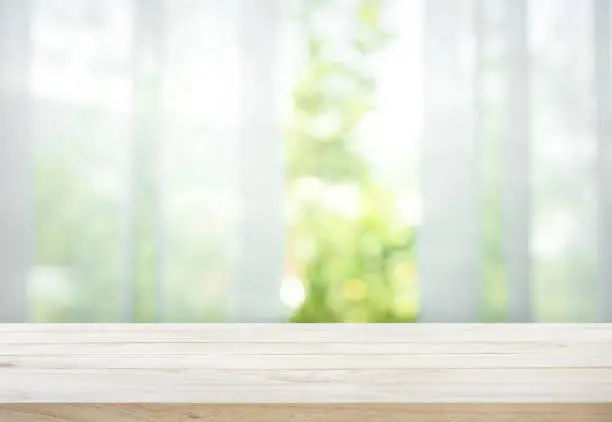 Photo of Wood table on blur of curtain with window view garden