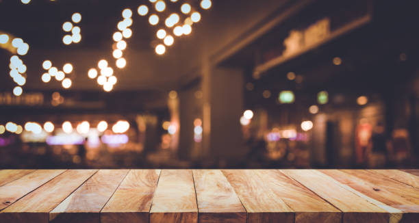 istock Wood table with blur light bokeh in dark night cafe 885452932