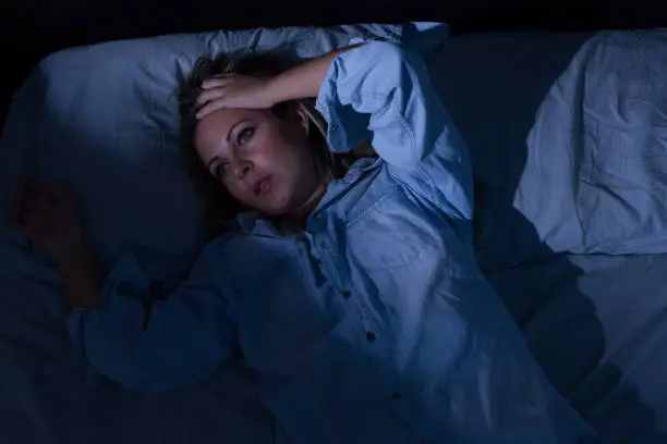 Sleep disorder, insomnia. Young blonde woman lying on the bed awake