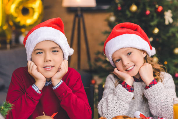 istock brother and sister in santa hats 885473982