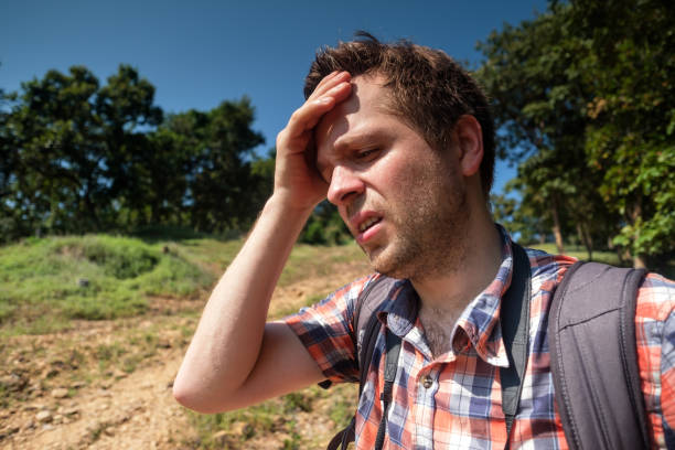 uomo stanco nella foresta unfder forte sole con zaino. viaggia solo in asia. soffrire forma colpo di sole - thirsty foto e immagini stock