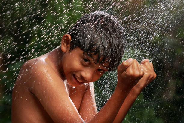A teenage girl is getting sprayed with a hose from a friend on a warm summer day.