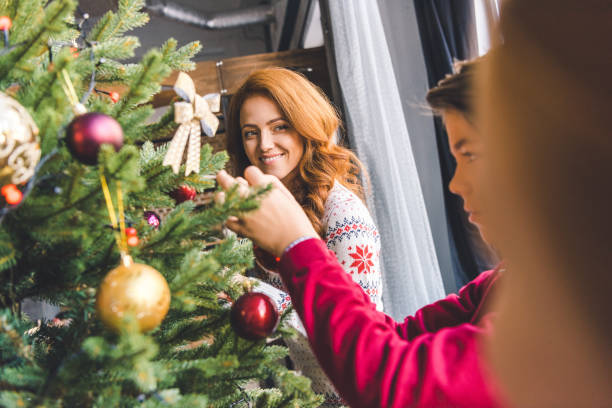 istock mother decorating christmas tree with kids 885499276
