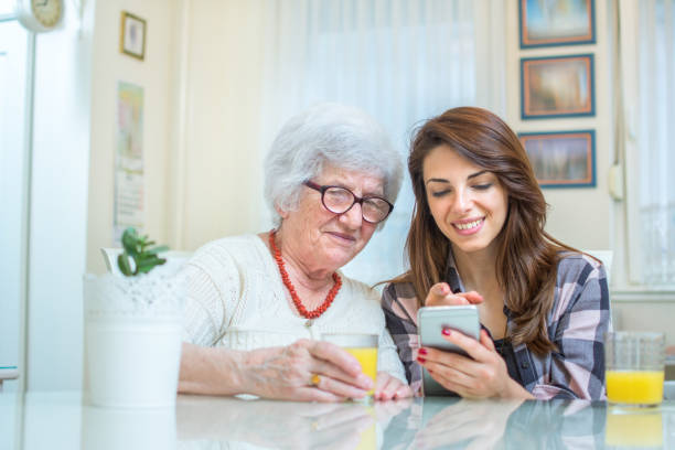 istock Young woman showing something on mobile phone to grandmother. 885515708