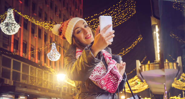 istock woman using a phone on he decorated street,christmas time 885516180