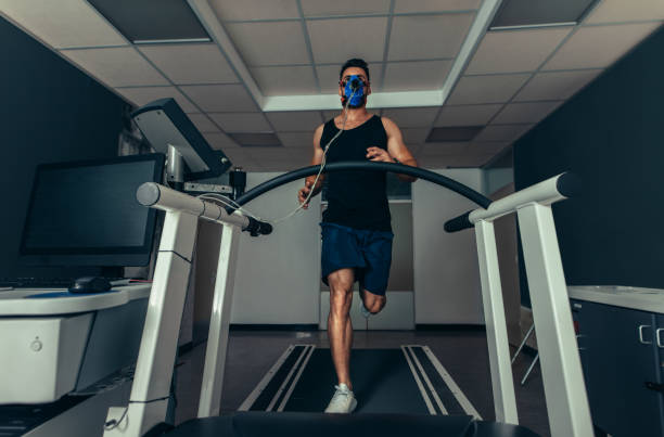 istock Fit man running fast on treadmill with a mask 885516370