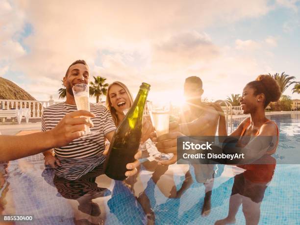 Happy Friends Cheering With Champagne In Pool Party At Sunset Rich People Having Fun In Exclusive Tropical Vacation Holiday And Friendship Concept Main Focus On Left Man Sun Tones Filter Stock Photo - Download Image Now
