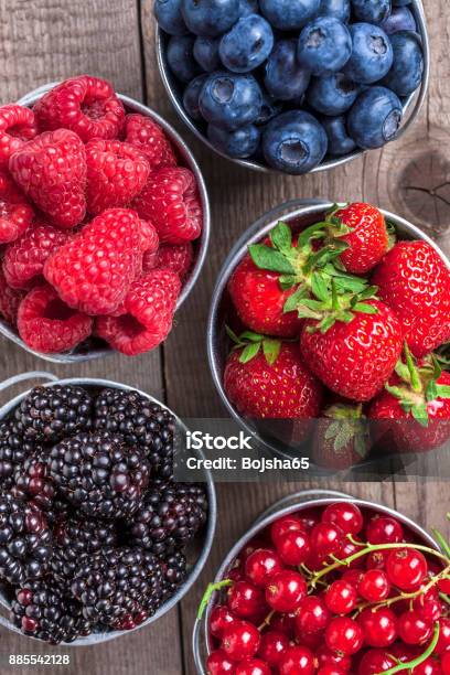 Berries Closeup Assortment In Tin Cans Overhead On Wooden Table Stock Photo - Download Image Now