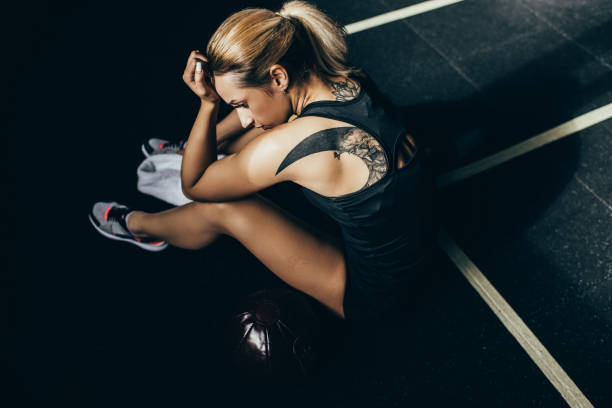 istock Exhausted sportswoman sitting on floor 885542858