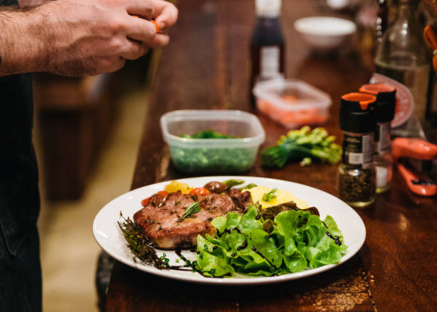 istock Stir fried pork steak served with vegetable side dish, salad and mash potato topping with balsamic dressing and red wine. 885545900