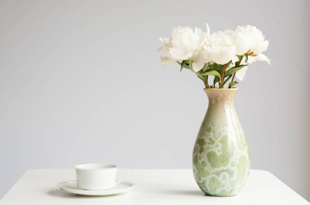 istock White peonies in green vase with tea cup 885554944