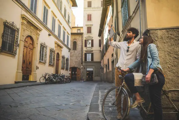 A couple of tourists visiting Florence, in Italy, during a warm and sunny summer day. The guidebook is a stunt copy.