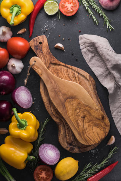 istock Two rustic cutting boards on the black kitchen table among fresh vegetables, herbs and spices. The concept of healthy and organic food. 885594970