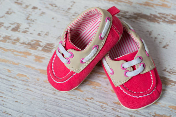 istock Baby red shoes on a rope against a white brick wall 885612108