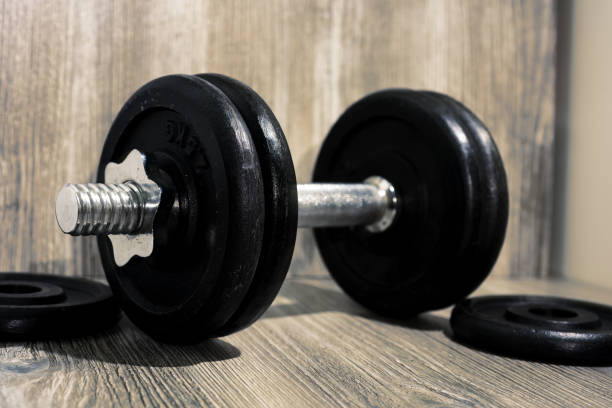 istock Black dumbbell on wooden background. 885655158