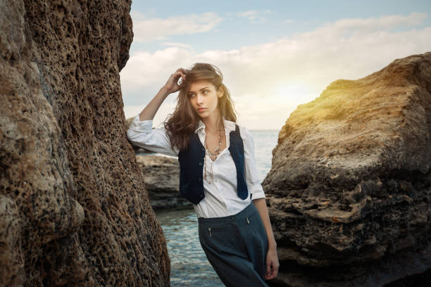 business woman on suit vest and white shirt standing near big stone on the sea cost beautiful brunett business woman on suit vest and white shirt standing near big stone on the sea cost life stile stock pictures, royalty-free photos & images