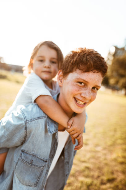 istock two lovely kids piggyback at the park 885712290