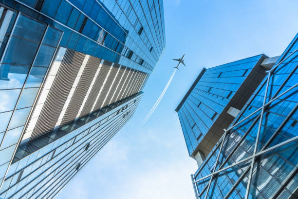 istock Low angle view of airplane flying over skyscrapers 885749858