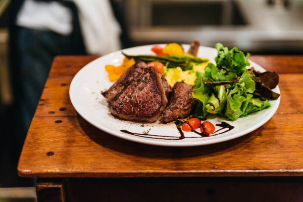 Stir fried beef steak served with vegetable side dish and salad topping with balsamic dressing.