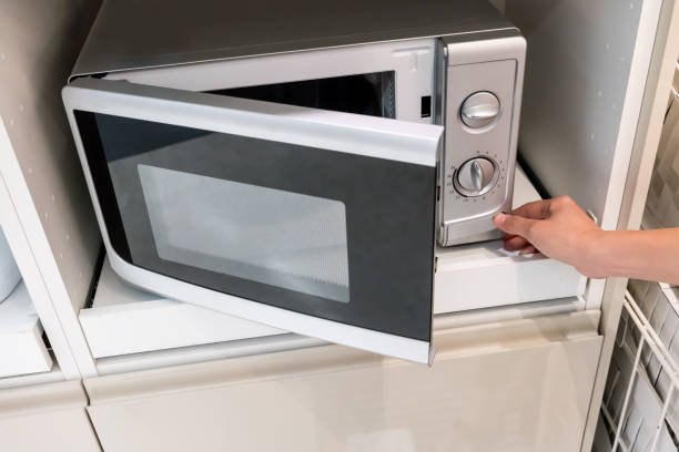 istock Woman's Hands pressing button to open microwave oven door 885762034