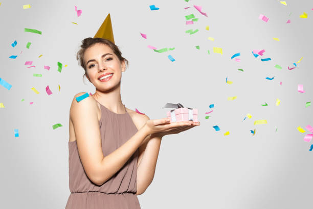 istock Young beautiful lady in festive hat holding New Year's gift 885764352