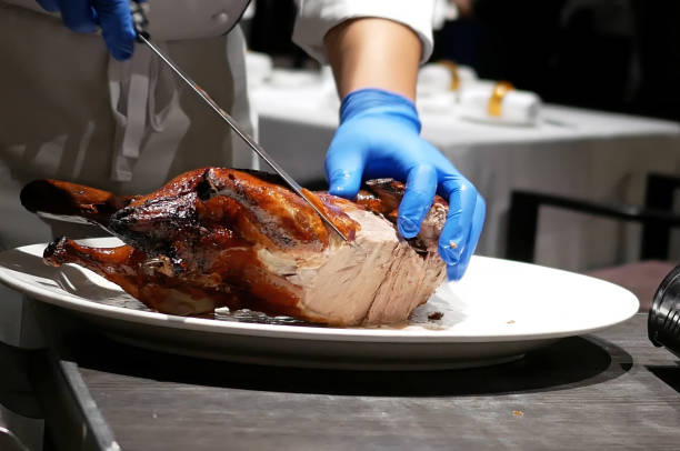istock Motion of chef cutting roasted duck into a plate for customer 885764512