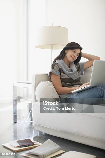 Foto de Mulher Usando O Laptop No Sofá e mais fotos de stock de Vida doméstica - Vida doméstica, Laptop, Pessoas