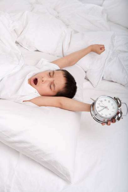 istock Little boy waking up with alarm clock 885851538