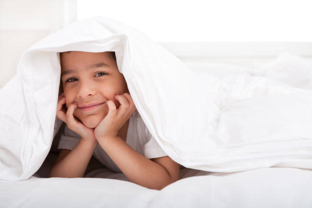 istock Smiling little boy under duvet 885852904