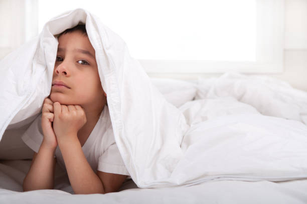 istock Sad little boy under duvet 885855932