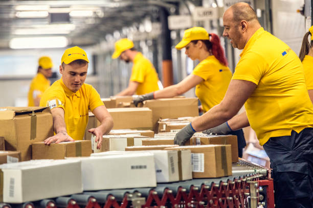 istock Delivery warehouse workers handling packages on conveyor belt 885902560