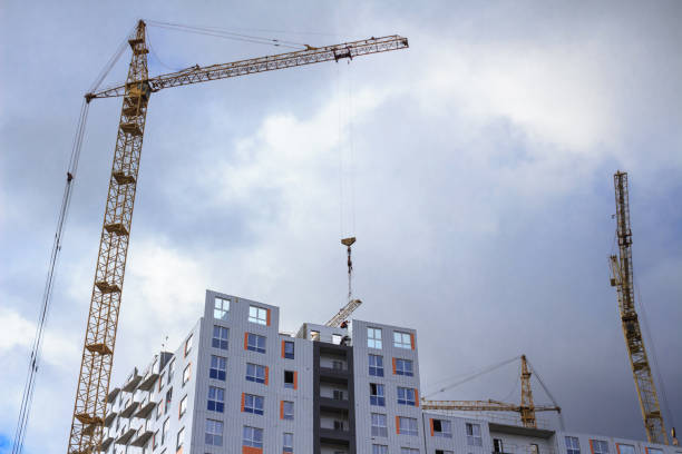 istock Working construction cranes and building. Rainy cloudy sky 885929124