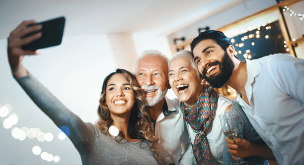 Christmas selfie. Closeup of a senior couple taking selfies with their grandson and his girlfriend at a Christmas party at home. family christmas party stock pictures, royalty-free photos & images