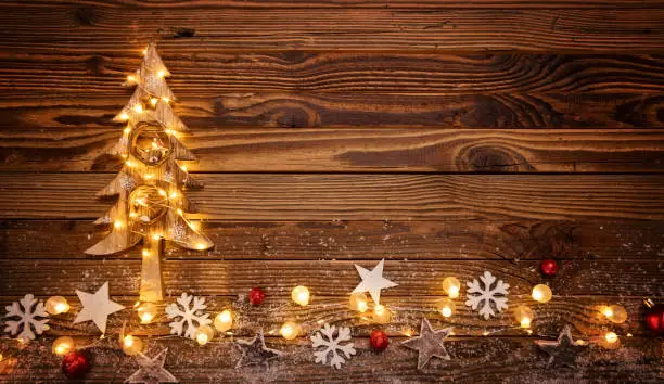 Christmas background with wooden decorations, tree and spot lights. Free space for text. Celebration and decorative design.