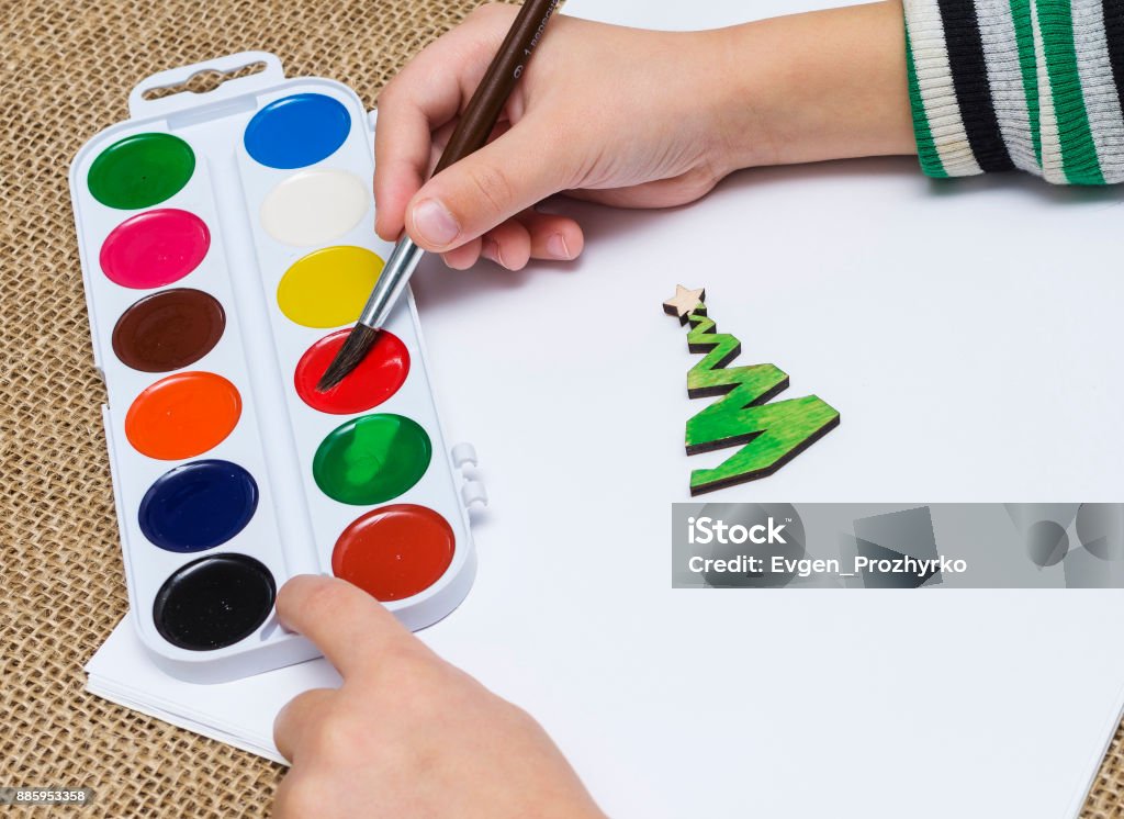 Die Hände des Kindes mit Pinsel malen einen Weihnachtsbaum mit Aquarellfarben. Lehren aus der Kreativität der Kinder. - Lizenzfrei Arm - Anatomiebegriff Stock-Foto